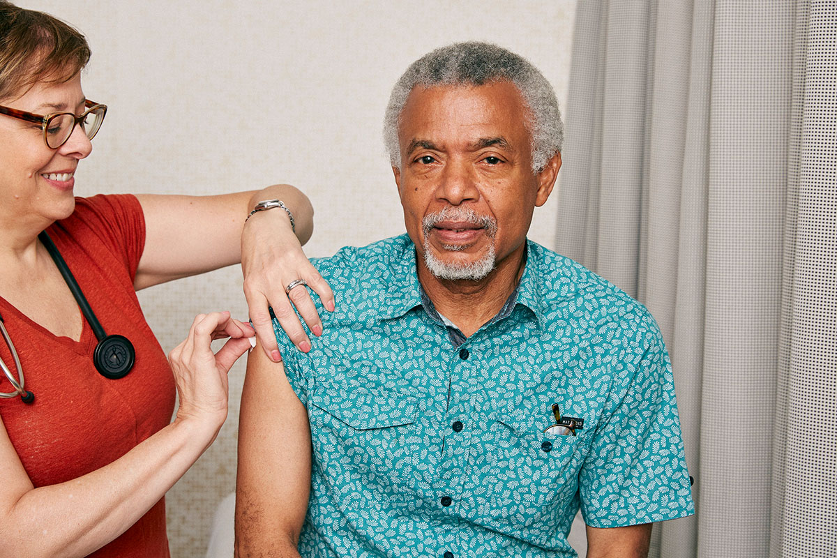 Older man having his upper arm cleaned before a shot