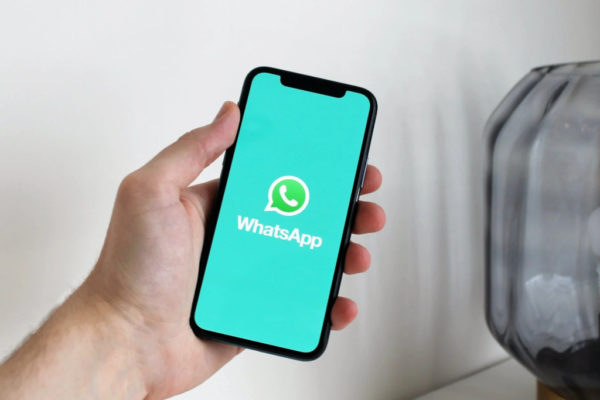 Holding mobile phone showing WhatsApp opening screen