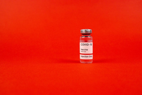 Covid-19 vaccine bottle against a red background