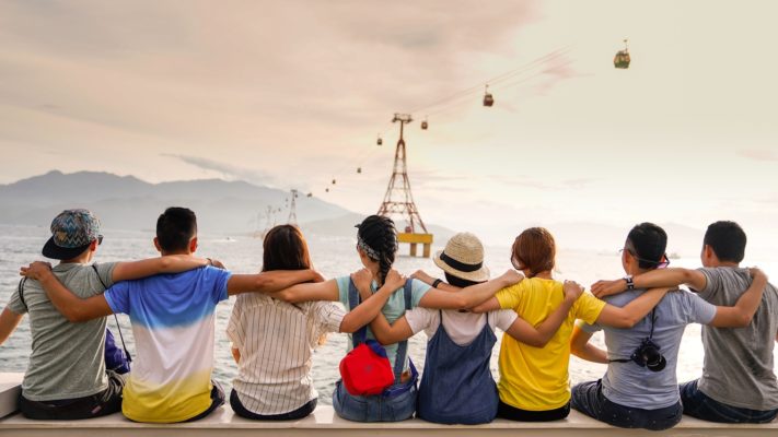 People holding shoulders sitting on a wall