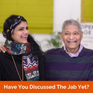 A young and senior person discussing the jab and laughing