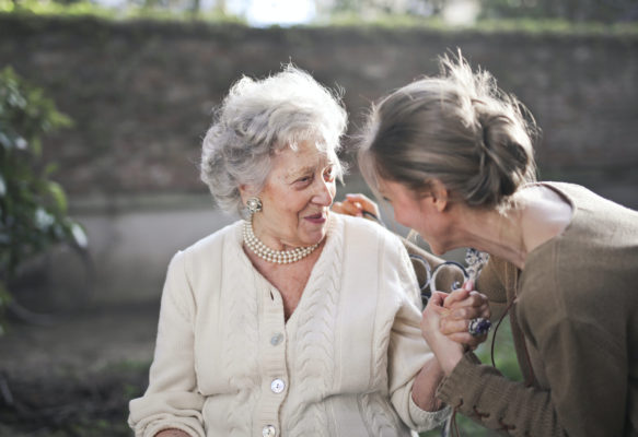 An elderly woman talking to a young woman