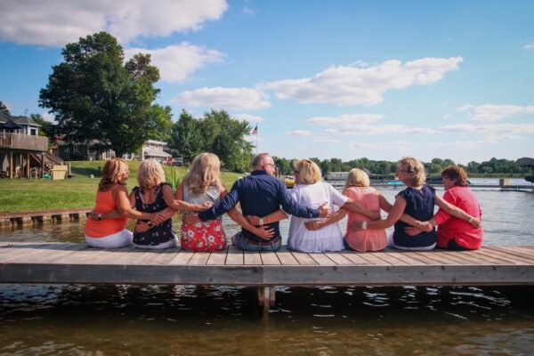 People holding each other while sitting on a dock