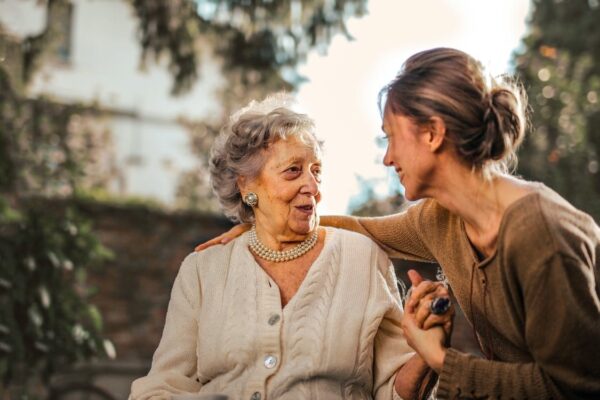 An elderly woman talking to a young woman