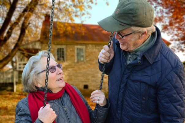 Two elderly people playing on a swing