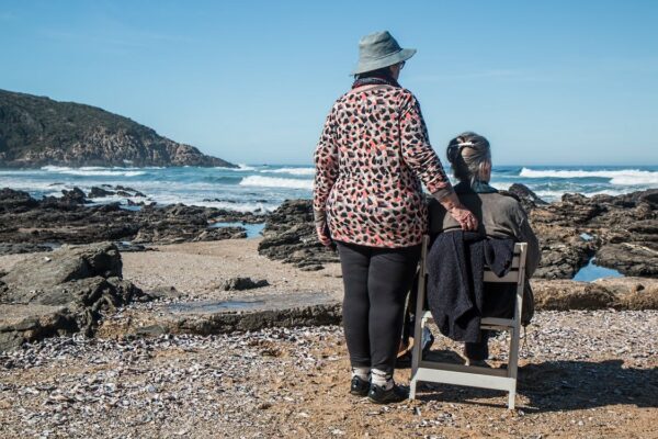 two elderly people watching the sea waves