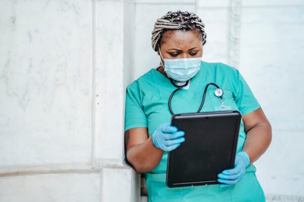 A female doctor with face mask looking at a tablet