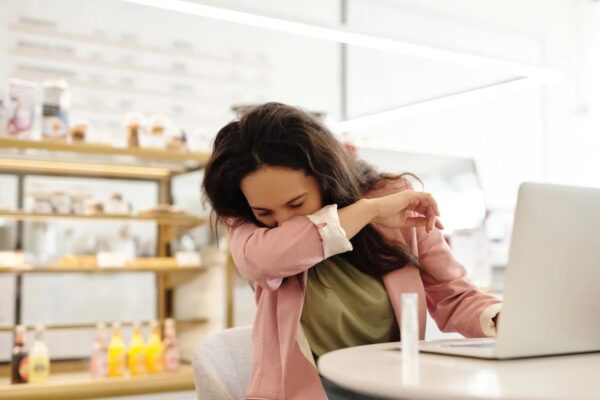 A woman sneezing in her armpit