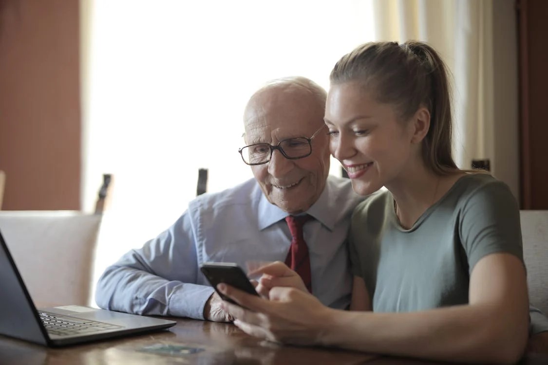Grandfather and granddaughter watching something on a mobile phone together