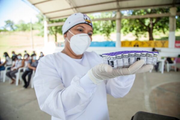 A medical professional with a mask holding vaccine vials