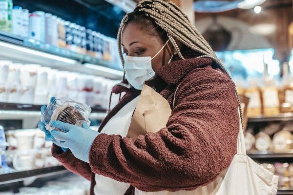 A woman in a food store with mask and surgical gloves