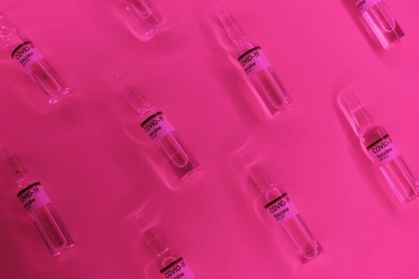 Covid-19 vaccine bottles against a pink background