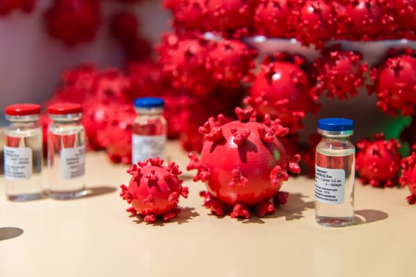 Models of viruses together with vaccines vials on a table