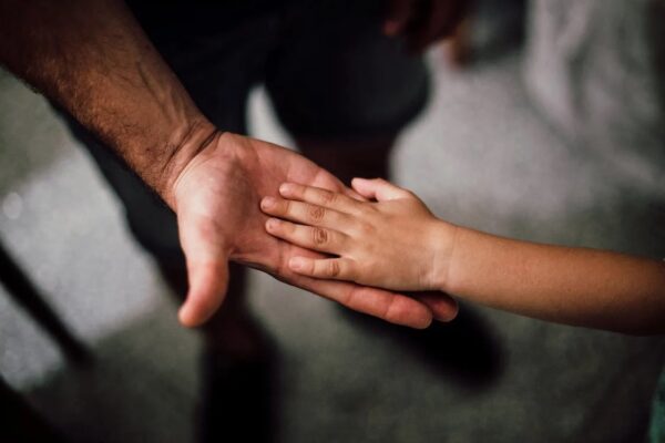 A man's hand holding a child's hand