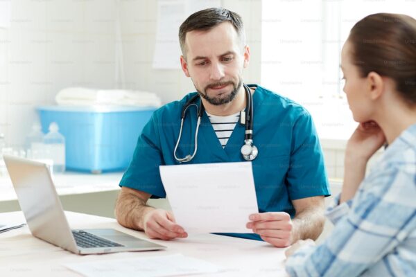 Doctor in uniform reading medical paper having appointment with one of patients in clinics