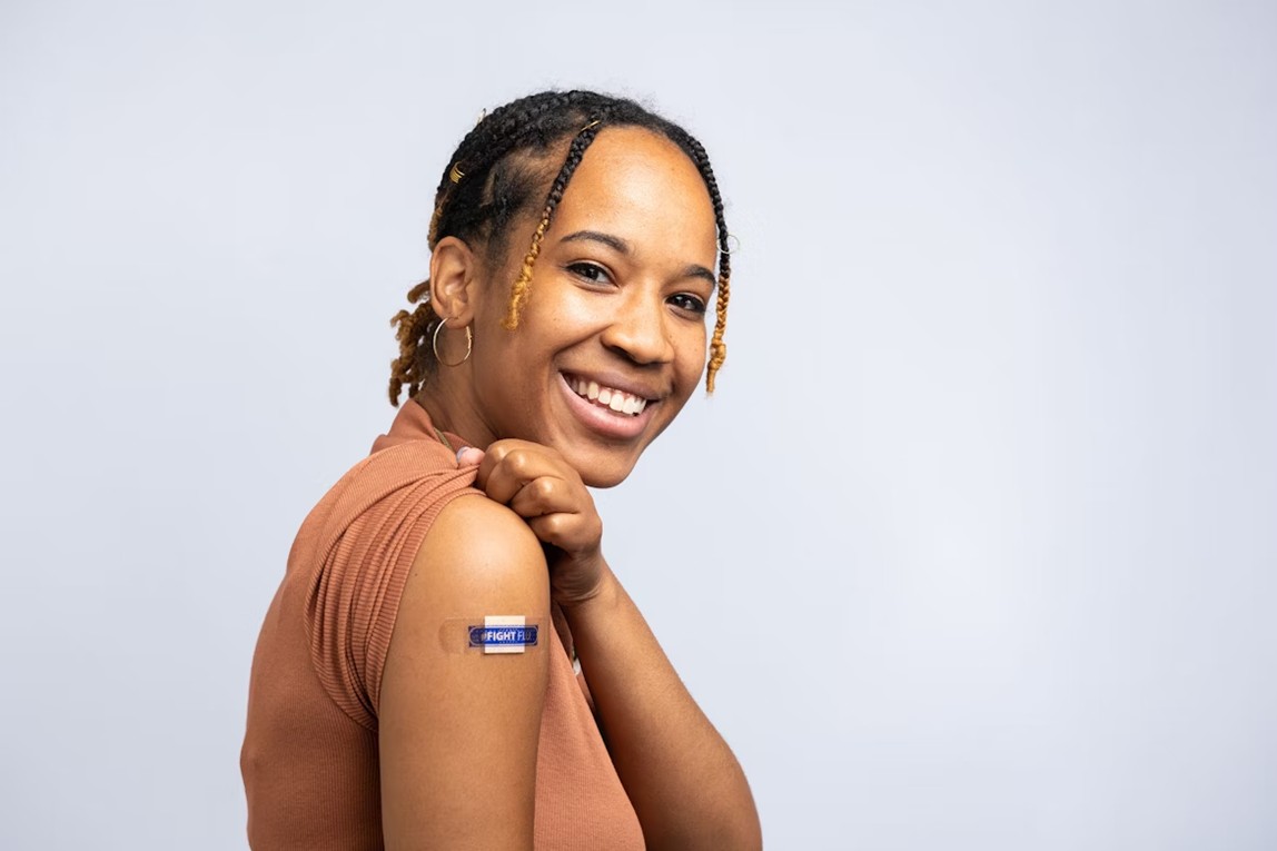 A woman showing her arm and smiling after receiving her annual flu vaccine.