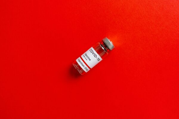 Close-up of a COVID-19 vaccine vial against a vivid red surface