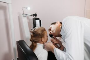 A doctor examines a young girl's ear during a medical appointment in a clinic.